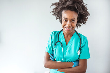 Portrait of female African American doctor standing in her office at clinic. Waist up portrait of beautiful African-American nurse posing confidently while standing with arms crossed 