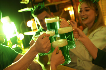 People with beer celebrating St Patrick's day in pub, focus on hands