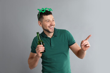 Happy man in St Patrick's Day outfit with beer on light grey background
