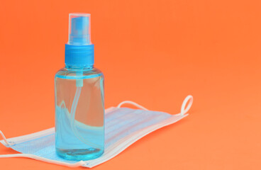 Hygienic and health measures. Hand sanitizer gel and surgical mask on orange background.