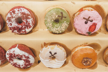 Fototapeta na wymiar Assorted tasty colorful donuts on display, close up view. Street food market