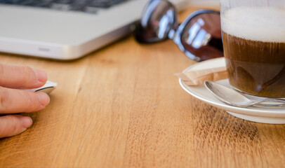 Person working in a cafe on a laptop with a coffee cortado served enjoying freedom of remote mobile working. Digital nomad freedom life style concept. Spain