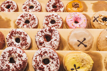 Assorted tasty colorful donuts on display, close up view. Street food market