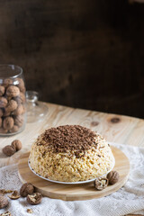 Traditional Russian anthill cake decorated with chocolate on light wooden background. Selective focus, vertical orientation, copyspace
