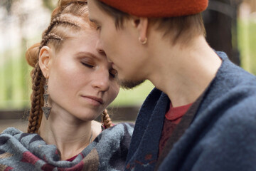 Couple in love, a girl with an original hairstyle and red hair and a guy in a hat, selected focus