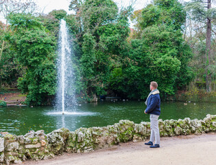 young man standing contemplating a stream of water on a lake