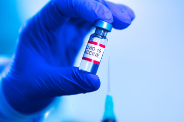 Obraz premium Vial with the vaccine for COVID-19 held by the hand of a doctor and in the other hand a syringe. Coronavirus vaccination concept