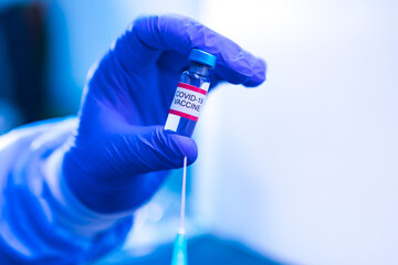 Obraz premium Vial with the vaccine for COVID-19 held by the hand of a doctor and in the other hand a syringe. Coronavirus vaccination concept
