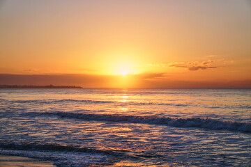 Sun rises over horizon dawn sea. Ocean at sunset. Sandy beach wave on seashore.