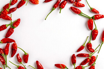 Red chili peppers are laid out on a white background in the form of a frame, a place for text - obrazy, fototapety, plakaty