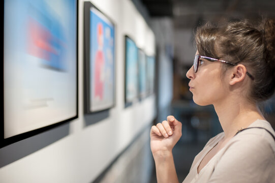 Young woman in modern art exhibition gallery hall contemplating artwork. Abstract painting