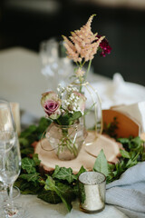 Vintage wedding decor. Beautiful event venue. Creative decoration. Hall decoration. Festive table decor. Stylish stone tablet with table number in grey, green branches and peonies, candles in gold can