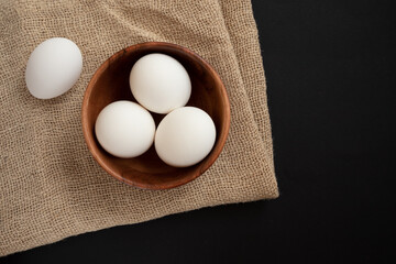 Raw chicken eggs in a wooden plate on the table.