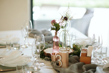 Vintage wedding decor. Beautiful event venue. Creative decoration. Hall decoration. Festive table decor. Stylish stone tablet with table number in grey, green branches and peonies, candles in gold can