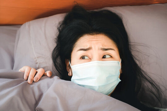 Depressed Asian Woman In Bed With Face Mask Scared And Panic Getting Sick Of Coronavirus