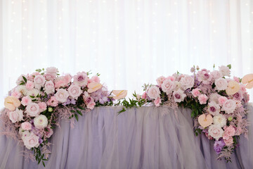 Vintage wedding decor. Beautiful event venue. Creative decoration. Hall decoration. Festive table decor. Stylish stone tablet with table number in grey, green branches and peonies, candles in gold can