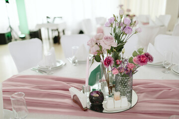 Vintage wedding decor. Beautiful event venue. Creative decoration. Hall decoration. Festive table decor. Stylish stone tablet with table number in grey, green branches and peonies, candles in gold can