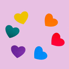 Handmade paper hearts in rainbow colors laid out in a circle on a pink background, copy space, flat lay.