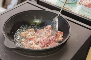 A huge cauldron stands on the stove of the summer kitchen. Tasty, juicy meat is fried in a...