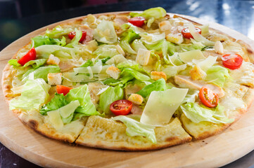 Pizza with prosciutto and rocket salad on wooden table.