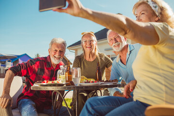 Senior people taking a selfie while having lunch in the backyard