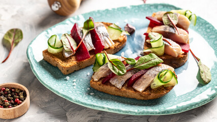 Sandwiches with herring, onions and beetroot salad, fresh cucumber. Tradition Danish open sandwich...