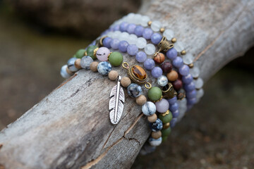collection of tiny mineral stones bracelets on wooden stick natural background