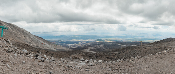 Top of crater Mount Etna volcano, frozen cold lava smokes, thick clouds