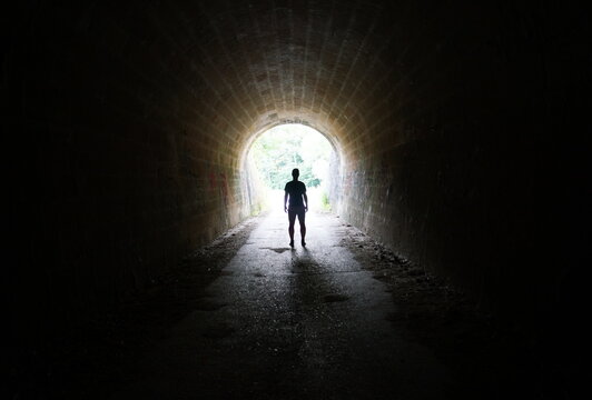 Escape the Darkness - silhouette of man standing in the light at the end of the tunnel