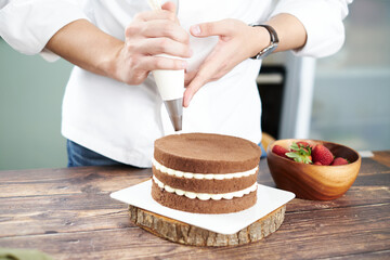 Pastry bakery chef in the kitchen decorating cake bakery and food concept.