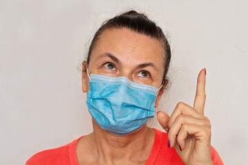 Woman aged in medical mask against coronavirus isolated on white rolled eyes finger up