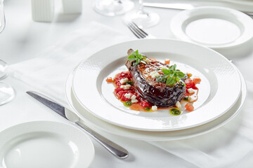 Half baked eggplants with meat, cheese and tomatoes on white background. Banquet festive dishes. Gourmet restaurant menu. White background.