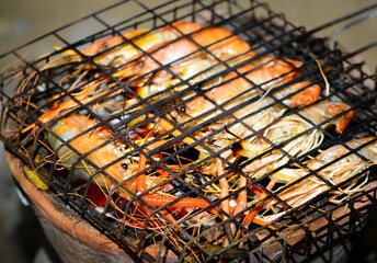 Big prawns are being grilled on the grill on a hot orange charcoal grill.