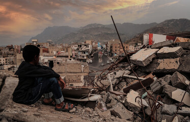 A child from Taiz City sits on the ruins of his ruined home because of the war on city-Yemen. - obrazy, fototapety, plakaty