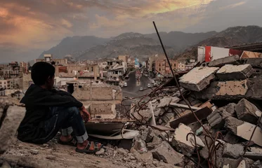 Fotobehang A child from Taiz City sits on the ruins of his ruined home because of the war on city-Yemen. © akram.alrasny