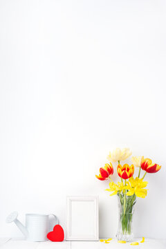 Beautiful tulip flowers in a vase with picture frame decoration on white wall.