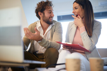 Fototapeta premium A young handsome businessman talking to a beautiful female colleague at a meeting in an apartment. Business, meeting, people