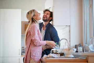 A happy couple having wonderful time while washing dishes together. Kitchen, housework, home, relationship