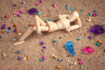 Fototapeta na wymiar a wooden mannequin lying on a beach among seashells