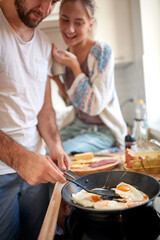 A young girl likes the breakfast prepared by her boyfriend. Cooking, together, kitchen, relationship