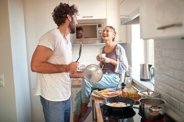 A young couple in love having fun while preparing a breakfast together. Cooking, together, kitchen, relationship