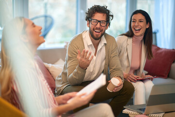 A group of young business people at a meeting laughing at jokes in a break of work. People,...