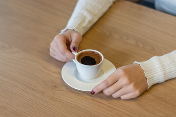 Fototapeta na wymiar The woman on the wooden table holding Turkish coffee with your hands