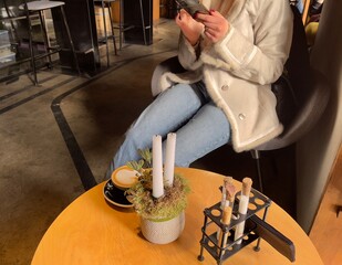 girl in stylish clothes holds a smartphone and drinks coffee