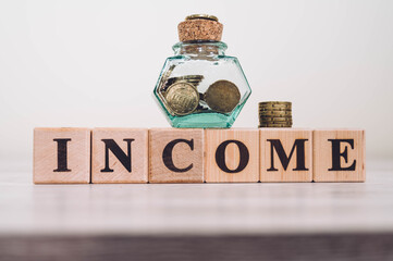 Word INCOME spelled on wood blocks. INCOME word written on wood blocks and coins on wooden table.
