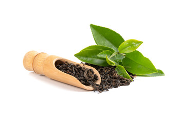 Dry tea in wooden spoons with green leaves.