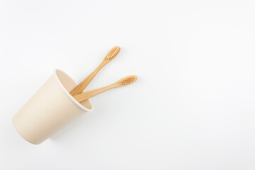 Two eco friendly bamboo toothbrushes in the paper cup.