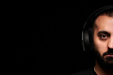 Close-up portrait of a musician dj in headphones on a black background
