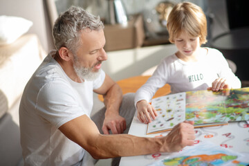 Elderly man and a boy reading a book together