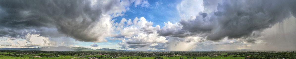 Panorama of the cloudy gray sky with storm running over a town in a valley in back of a mountain covered, Dark sky dramatic black cloud before the rain. rainy storm over rice fields, Thailand